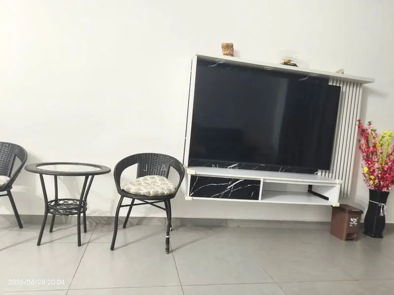 Living features: white painted walls, grey tile flooring, wall-mounted TV, white TV console with marble accents, black round coffee table, 2 black woven chairs with cushions, decorative flower arrangement, small decorative items on TV console; style: modern.