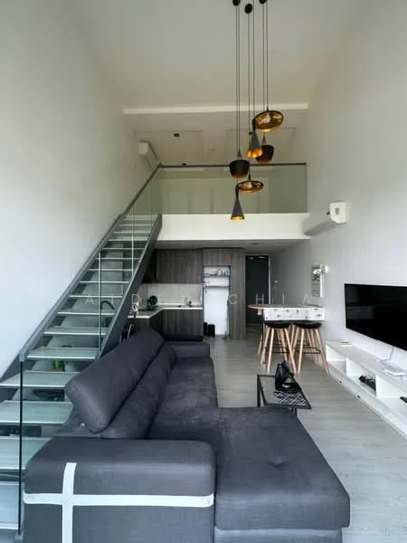 Living features: grey fabric L-shape sectional sofa, glass coffee table, wall-mounted TV, white TV console, pendant lighting with multiple bulbs, exposed staircase with glass railing, light wood flooring, air conditioning unit, decorative wall with dark cabinetry, open-plan layout; style: modern.