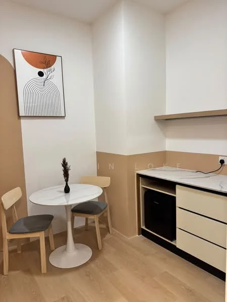 Dining features: round white dining table, 2 wooden dining chairs with grey cushions, light wood flooring, cream painted walls, brown accent wall, marble countertop, black cabinetry, small refrigerator, decorative wall art; style: modern.