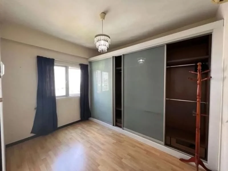 Bedroom features: wooden flooring, white painted walls, sliding glass wardrobe with frosted panels, single window with sheer curtains, chandelier light fixture, clothes rack, corner for additional furniture; style: modern.