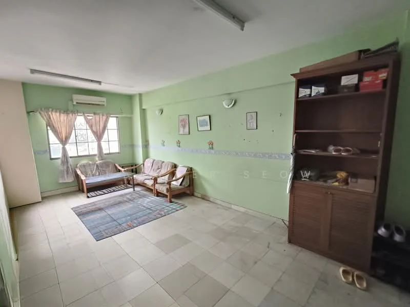 Living features: green painted walls, tile flooring, 2-seater wooden sofa, 3-seater wooden sofa, area rug with geometric pattern, window with sheer curtains, wall-mounted air conditioning unit, built-in wooden shelf, decorative wall art, light fixtures on walls.