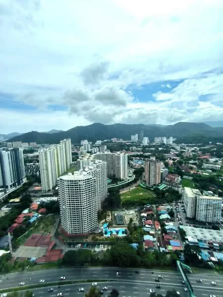 Exterior type: high-rise condominium; features: city skyline view, surrounded by greenery, multiple high-rise buildings, swimming pool visible, mountain backdrop, urban landscape, roadway in foreground; style: modern.
