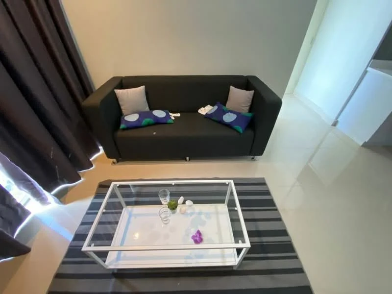 Living features: black fabric sofa, decorative cushions with blue and green patterns, glass coffee table, striped area rug, floor-to-ceiling curtains, cream painted walls, glossy tile flooring, natural light from window; style: modern.