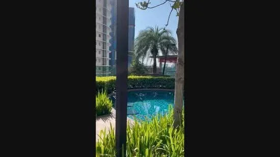 Exterior type: high-rise condominium; features: infinity pool, landscaped garden with greenery, palm trees, glass railing, pool deck, surrounding greenery; style: modern.