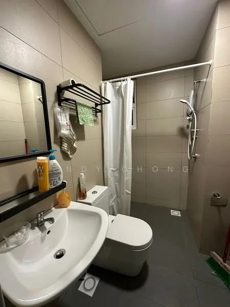 Bathroom features: white ceramic sink, chrome basin mixer faucet, white toilet, shower with glass enclosure, handheld shower, white shower curtain, grey tiled walls, dark grey tiled flooring, black framed mirror, wall-mounted towel rack, soap dispenser, cleaning supplies on floor; style: modern.