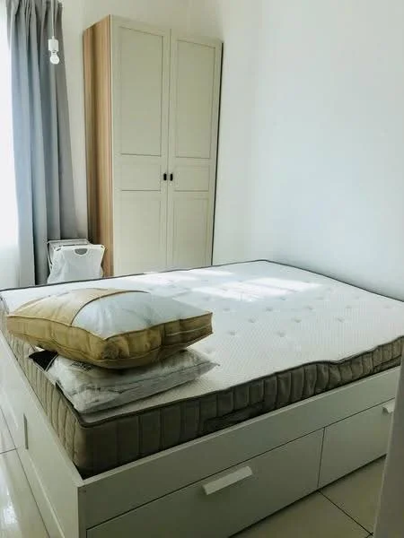 Bedroom features: queen-size bed, mattress with bedding, decorative pillow, built-in wardrobe with two doors, white painted walls, grey curtains, tile flooring, natural light from window; style: minimalist.