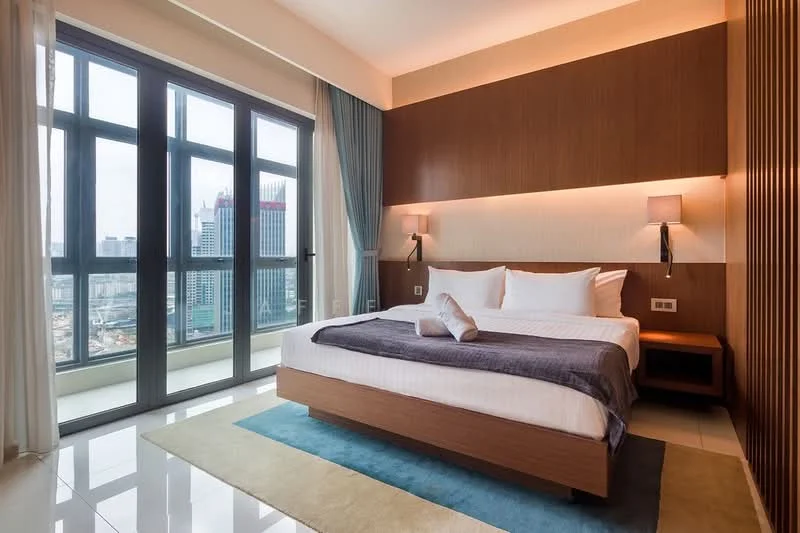 Bedroom features: king-size bed with white bedding, upholstered headboard, wooden bedside tables, wall-mounted sconces, floor-to-ceiling windows, city skyline view, light blue curtains, cream painted walls, polished tile flooring, area rug with geometric pattern, decorative throw blanket; style: modern; view: city.