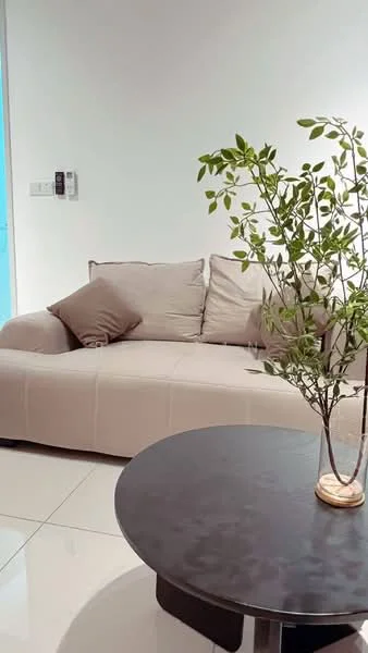Living features: beige fabric sofa, decorative cushions, round black coffee table, ceramic vase with plant, white painted walls, glossy tile flooring, wall-mounted intercom, natural light from window; style: modern.
