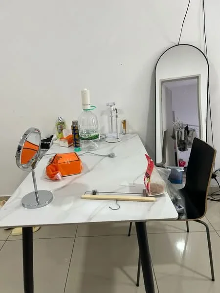 Room features: marble tabletop, black legs on table, mirror with thin frame, makeup mirror, plastic container, glass bottle, various personal items, ceramic bowl, chair with wooden legs, floor tiles, white painted walls; style: modern.