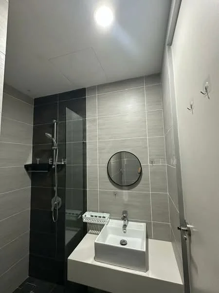 Bathroom features: grey tiled walls, black tiled flooring, walk-in shower with glass enclosure, rain shower head, handheld shower, round mirror, single-bowl sink, chrome basin mixer faucet, wall-mounted shelf, white cabinet under sink, recessed ceiling light; style: modern.