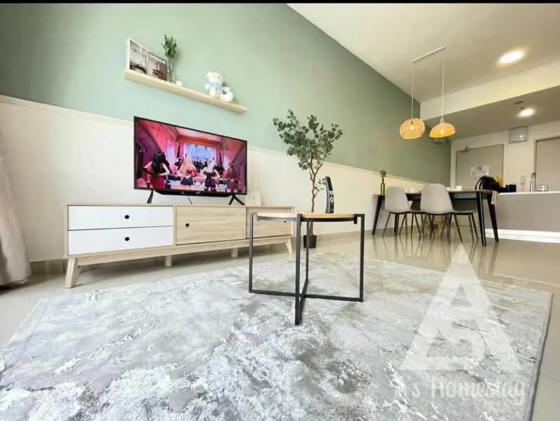 Living features: light green painted walls, white ceiling, 3-seater wooden TV console, wall-mounted TV, decorative plant in pot, area rug with geometric pattern, coffee table with black metal frame, pendant lighting, dining area visible in background, grey upholstered dining chairs; style: modern.