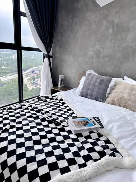Bedroom features: king-size bed, white bedding, black and white checkered throw blanket, grey decorative pillows, floor-to-ceiling windows, curtains in dark blue, concrete walls, nightstand, magazine on bed; style: modern; view: city.