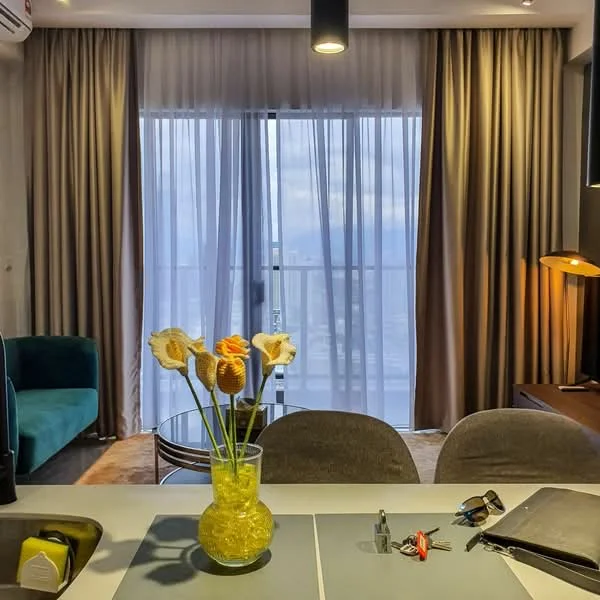Living features: floor-to-ceiling windows, sheer curtains, grey accent wall, recessed downlights, pendant lamp, green fabric sofa, glass coffee table, decorative vase with flowers, wooden console table, study desk, office chair, keys on table, wall-mounted air conditioning unit; style: modern; view: city.