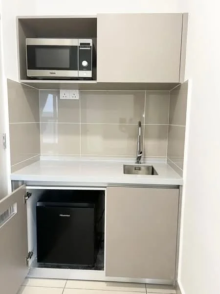 Kitchen features: grey cabinetry, white countertop, single-bowl stainless-steel sink, chrome pull-down faucet, built-in microwave, black mini fridge, ceramic tile backsplash, wall-mounted electrical outlets, under-cabinet lighting, tile flooring; style: modern.