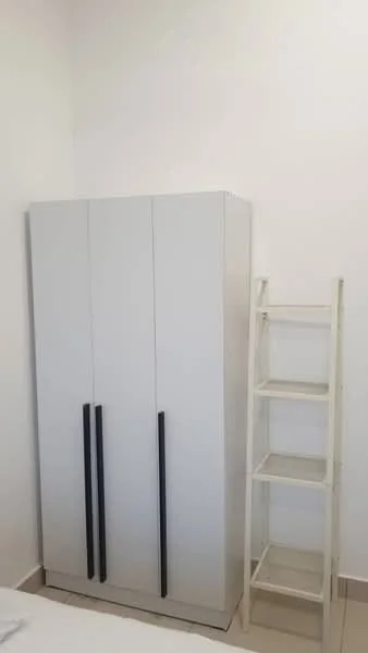 Room features: white painted walls, light-colored tiled flooring, three-door wardrobe with black handles, open shelving unit, minimalist design; style: modern.