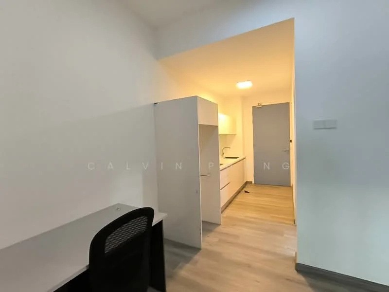 Room features: light wood laminate flooring, white painted walls, built-in cabinetry, kitchenette with white cabinets, countertop, single-bowl stainless-steel sink, recessed ceiling lights, door leading to another room, desk with black chair; style: modern.