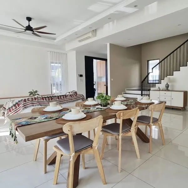 Dining features: 6-seater wooden dining table, light wood dining chairs with cushions, decorative table runner, white ceramic dinnerware, potted plant on table, pendant light above table, large windows with sheer curtains, white tiled flooring, ceiling fan with dark blades, open-plan layout to living area, wall-mounted cabinet in background, staircase visible in background; style: modern. Living features: fabric sofa with patterned throw, decorative cushions on sofa, coffee table in front of sofa, area rug under coffee table, wall-mounted TV, sideboard with decorative items, white walls, recessed ceiling lights; style: modern.
