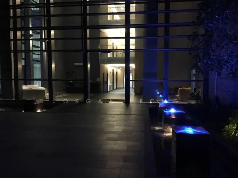 Exterior type: high-rise condominium; features: glass curtain wall, illuminated water features, paved walkway, outdoor seating area, landscaped greenery, modern architectural design, night lighting, open lobby area; style: modern.