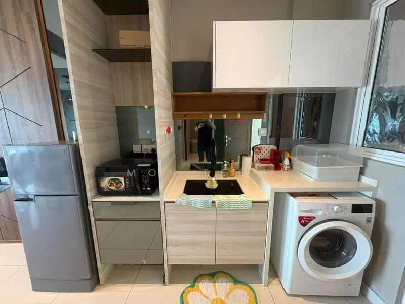 Kitchen features: grey cabinetry, white countertop, single-bowl stainless-steel sink, chrome pull-down faucet, built-in microwave, stainless-steel fridge, freestanding washing machine, ceramic tile flooring, wall-mounted cabinets, kitchen towel rack, decorative rug with floral pattern, window with sheer curtains; style: modern.