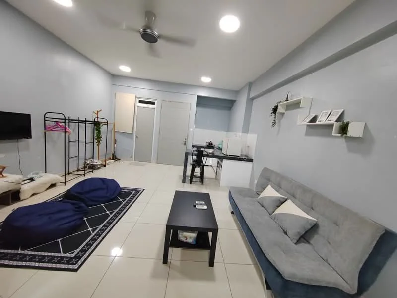 Living features: grey fabric sofa, black coffee table, area rug with geometric pattern, wall-mounted TV, ceiling fan, white painted walls, tile flooring, decorative shelves, bean bags, clothing rack, dining table with chairs, kitchenette area; style: modern.