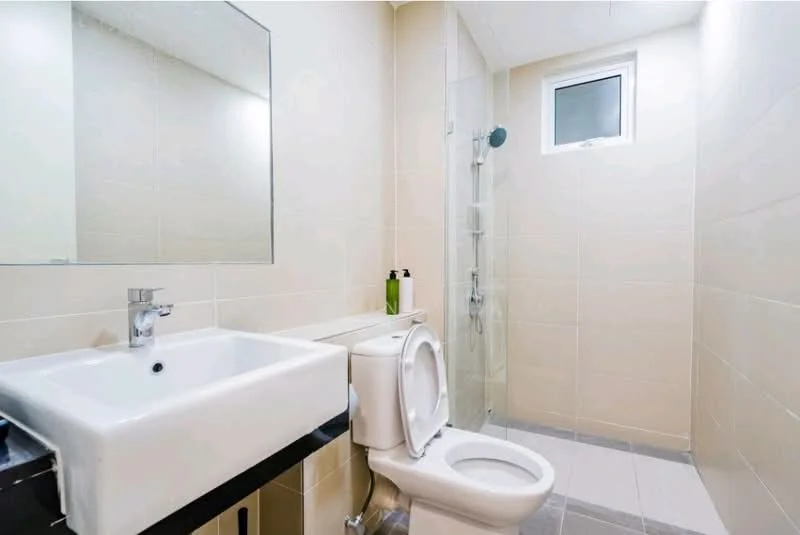 Bathroom features: white ceramic sink, chrome basin mixer faucet, white toilet, shower with glass enclosure, wall-mounted showerhead, tile cladding on walls, grey tile flooring, mirror above sink, window for natural light; style: modern.