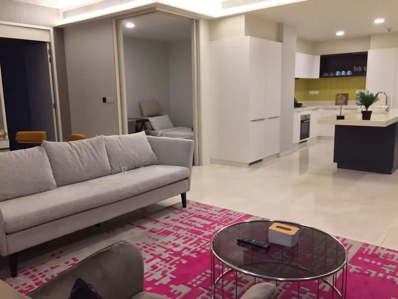 Living features: 3-seater fabric sofa in light grey, coffee table with glass top, area rug with geometric pattern in pink and grey, wall-mounted TV, decorative plant in pot, open layout to kitchen, marble flooring, recessed downlights; style: modern. Kitchen features: white cabinetry, kitchen island with countertop, built-in oven, stainless-steel range hood, 4-burner gas hob, green backsplash, refrigerator, dishwasher; style: modern. Room features: sliding door to another room, neutral wall color, soft seating area.