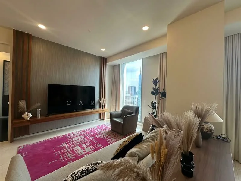 Living features: large floor-to-ceiling windows, city skyline view, light-colored walls, wood panel accent wall, flat-screen TV on wall-mounted console, grey upholstered armchair, decorative plants, area rug with abstract pattern in pink, sofa with decorative cushions, coffee table, recessed ceiling lights; style: modern; view: city.