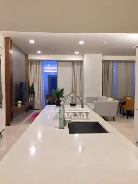 Kitchen features: white quartz countertop, single-bowl stainless-steel sink, chrome pull-down faucet, built-in cabinetry, recessed downlights, open layout, view of living area, marble tile flooring; style: modern. Living features: sofa in light fabric, armchairs in yellow upholstery, coffee table, TV console, floor-to-ceiling windows with sheer curtains, decorative plants, area rug, recessed downlights; style: modern.