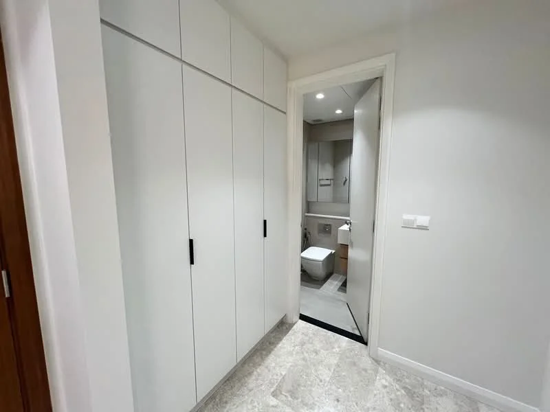 Room features: white cabinetry with flat-panel doors, black handles, light grey walls, marble tile flooring, door leading to bathroom, recessed downlights, neutral color palette; style: modern.