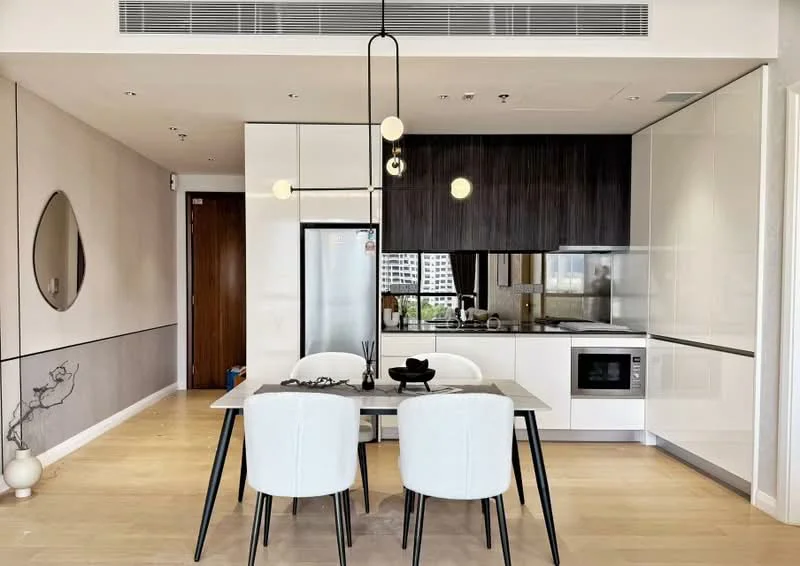 Dining features: 6-seater dining table, white upholstered dining chairs, pendant light fixture, wooden flooring, open-plan layout, kitchen with white cabinetry, black countertop, built-in microwave, stainless-steel fridge, kitchen island, window with city view, decorative wall art, wall-mounted cabinets; style: modern; view: city.