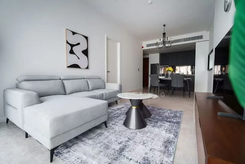 Living features: L-shape sectional sofa in light grey, round coffee table with black base, area rug with geometric pattern, wall-mounted TV, wooden TV console, chandelier with multiple bulbs, white painted walls, light-colored flooring, decorative artwork on wall; style: modern.