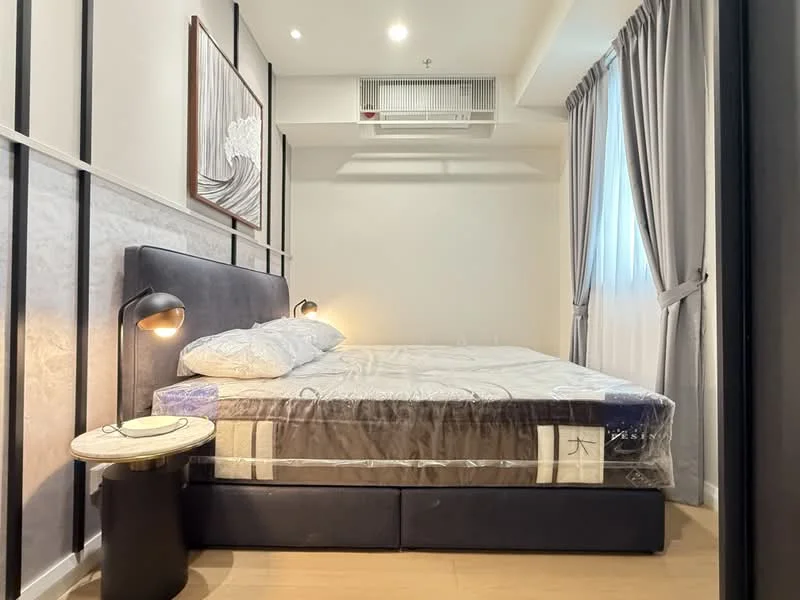 Bedroom features: king-size bed with mattress protector, upholstered headboard, bedside table with lamp, floor-to-ceiling window with sheer curtains, light grey curtains, wall-mounted split AC, wooden flooring, decorative wall paneling, recessed ceiling lights; style: modern.