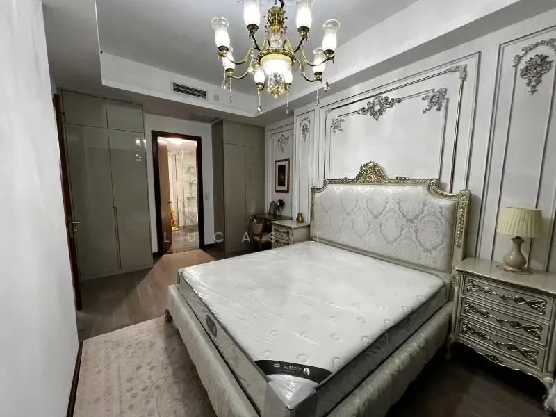 Bedroom features: king-size bed with upholstered headboard, decorative wall paneling, chandelier with multiple bulbs, two bedside tables with lamps, built-in wardrobe with sliding doors, wooden flooring, area rug, framed artwork on wall; style: luxury.