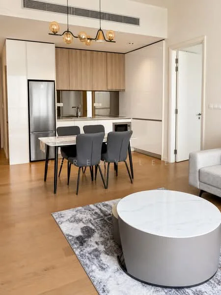 Living features: light wood flooring, white walls, recessed downlights, 5-blade ceiling fan, dining table with 4 grey upholstered chairs, marble-top coffee table, area rug with abstract pattern, stainless-steel fridge, built-in microwave, kitchen cabinetry with wood finish, open kitchen layout, countertop with backsplash; style: modern.