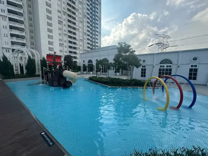 Exterior type: swimming pool deck; features: infinity pool, water slide, colorful water play structures, surrounding landscaped gardens, manicured lawn, paved walkway, high-rise condominium in background, power lines visible in background; style: modern.