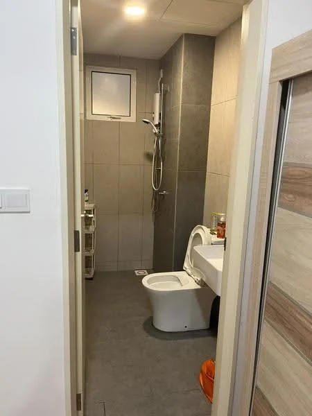 Bathroom features: grey tile flooring, grey wall tiles, white toilet, wall-mounted shower with adjustable head, chrome shower faucet, glass shower enclosure, small window for ventilation, white sink with cabinet, towel rack, storage cart, orange floor mat; style: modern.