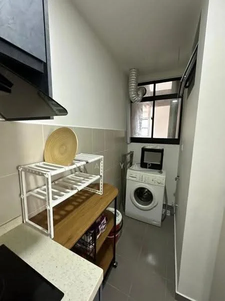 Laundry features: white washing machine, wooden shelving unit, grey tiled flooring, white walls, window with black frame, ventilation duct, countertop with cream surface, storage basket; style: modern.