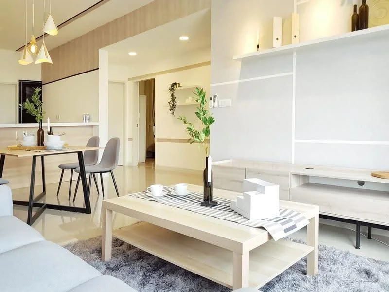 Living features: 3-seater fabric sofa in light grey, coffee table with wooden top, area rug with plush texture, pendant lighting with multiple bulbs, wall-mounted TV console, decorative wall shelf, decorative plants in vase, dining table with 4 chairs, open layout with kitchen view, neutral painted walls, recessed downlights, floor-to-ceiling windows; style: modern.