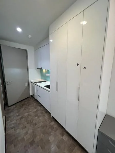 Kitchen features: white cabinetry, built-in oven, stainless-steel cooktop, single-bowl stainless-steel sink, chrome pull-down faucet, light grey walls, laminate flooring, recessed downlights, flat-panel cabinet doors, countertop with backsplash, storage cabinets, door leading to hallway; style: modern.