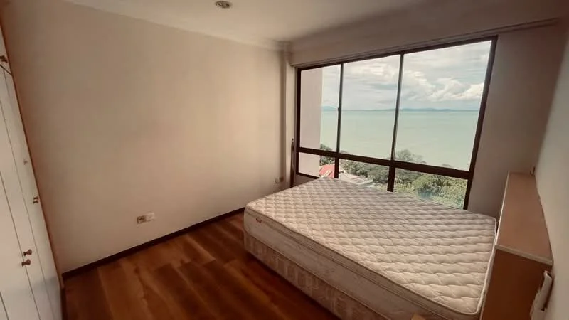 Bedroom features: large floor-to-ceiling windows, sea view, wooden flooring, white painted walls, built-in wardrobe, unfurnished with mattress, natural light, neutral color scheme; style: modern; view: sea.