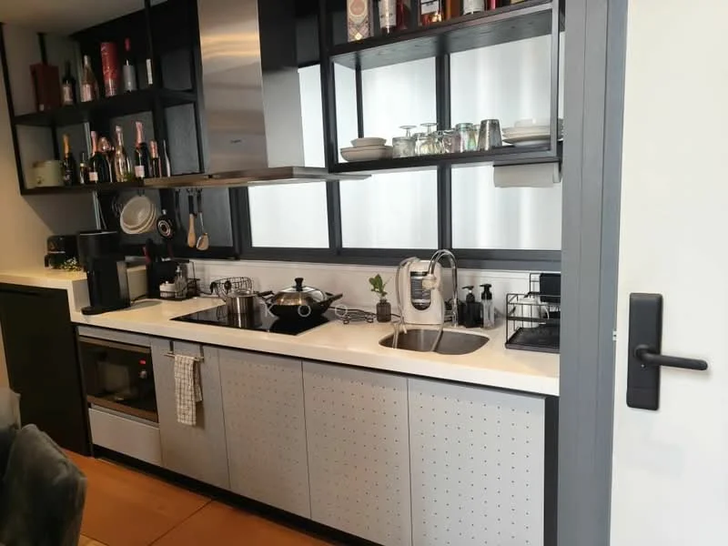 Kitchen features: stainless-steel sink, chrome pull-down faucet, white quartz countertop, black cabinetry with perforated design, open shelving, built-in microwave, freestanding coffee machine, kettle, various glassware and utensils, black dish rack, cooking pots and pans, wall-mounted storage for kitchen tools; style: modern.