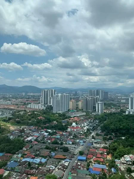Exterior type: high-rise condominium; features: city skyline view, surrounded by residential areas, mixed-use development, green hills in background, urban landscape, high-rise buildings, low-rise houses, road network visible; style: modern.