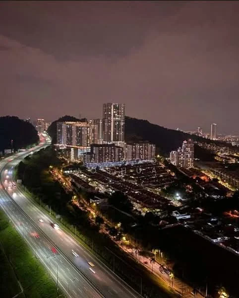 Exterior type: high-rise condominium; features: glass curtain wall, illuminated facade, surrounded by greenery, adjacent to highway, multiple high-rise buildings, night view, urban skyline in background; style: modern.