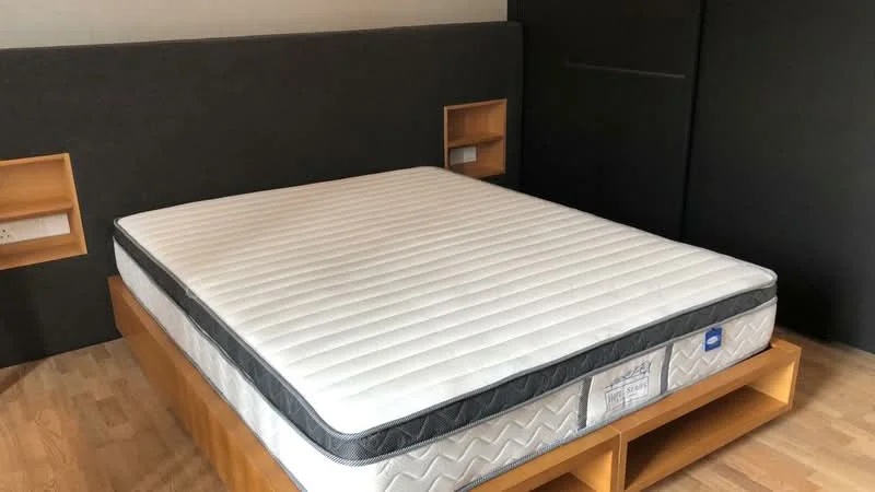 Bedroom features: queen-size bed, wooden bed frame, grey upholstered headboard, built-in bedside shelves, laminate flooring, neutral wall color, minimalist decor; style: modern.