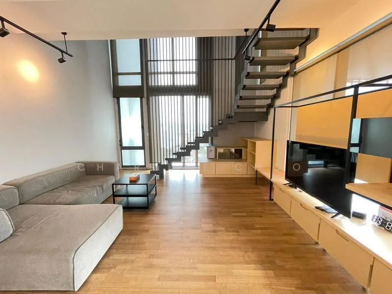 Living features: L-shape sectional sofa in grey fabric, wooden coffee table, TV console with built-in storage, wall-mounted TV, wooden flooring, large windows with vertical blinds, exposed staircase with metal railing, recessed ceiling lights, open layout, decorative wall paneling; style: modern.