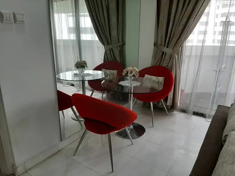 Dining features: round glass dining table, 4 red upholstered chairs, mirrored wall, white marble flooring, sheer curtains, decorative vase with flowers; style: modern.