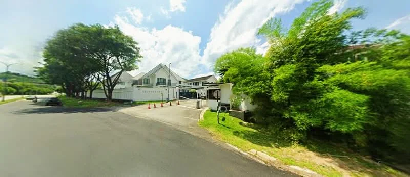 Exterior type: detached bungalow; features: white painted facade, flat roof, manicured lawn, mature trees, paved driveway, surrounded by greenery, visible parking area, security cones, gated entry; style: modern.