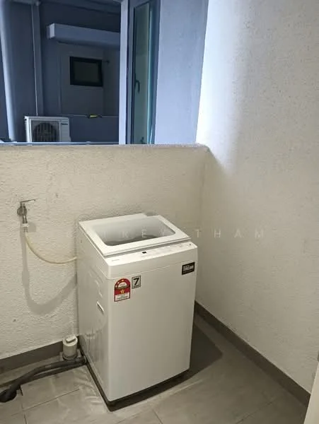 Laundry features: top-load washing machine in white, grey tiled flooring, white painted walls, window for natural light, plumbing connection visible, drainage outlet, small wall-mounted shelf, space for additional storage.