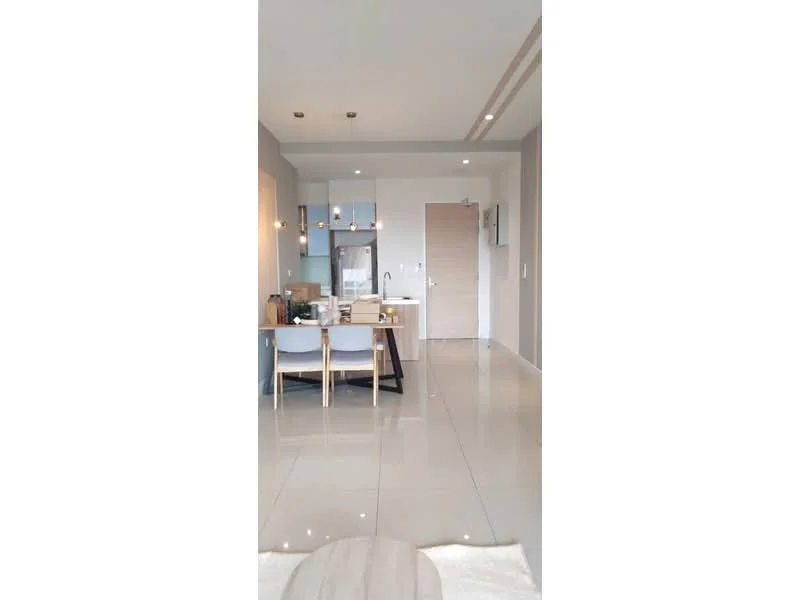 Living features: glossy tile flooring, light grey painted walls, recessed downlights, pendant lighting, open-plan layout, kitchen island with seating, stainless-steel fridge, wooden dining table with chairs, wall-mounted TV, sliding door, neutral color palette, decorative wall art; style: modern.