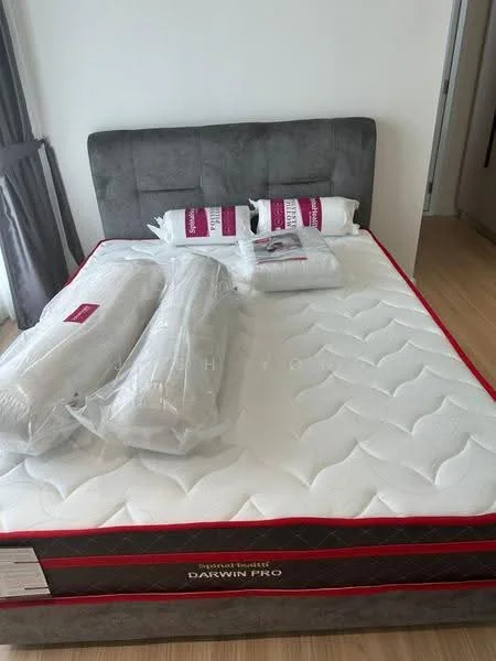 Bedroom features: queen-size bed, upholstered headboard in grey, mattress with protective cover, two large pillows with protective covers, two bolster pillows with protective covers, wooden flooring, curtains in grey, neutral wall color; style: modern.